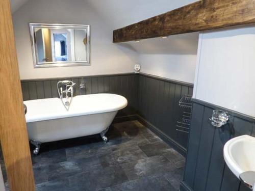 a bathroom with a bath tub and a sink at Little Owl Barn in Warslow