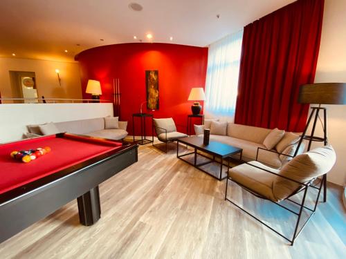 uma sala de estar com uma mesa de bilhar e paredes vermelhas em DORMERO Hotel Dresden City em Dresden