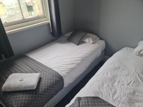 a small bedroom with two beds and a window at Kearsley Hotel in Cessnock