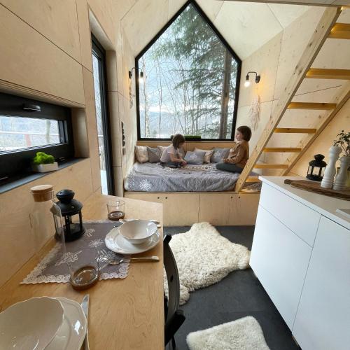two children sitting on a bed in a tiny house at Domek na drzewie Ceprowo in Szczyrk