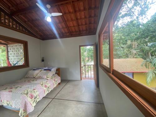 a bedroom with a bed and a large window at Chalés Cumuruxatiba in Cumuruxatiba
