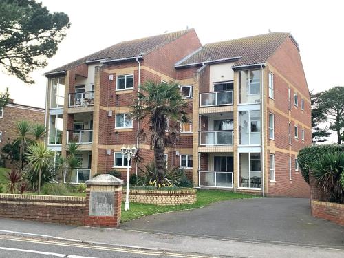 an apartment building with a palm tree in front of it at Top Floor Sandbanks Apartment with Free Parking just minutes from the Beach and Bars in Canford Cliffs