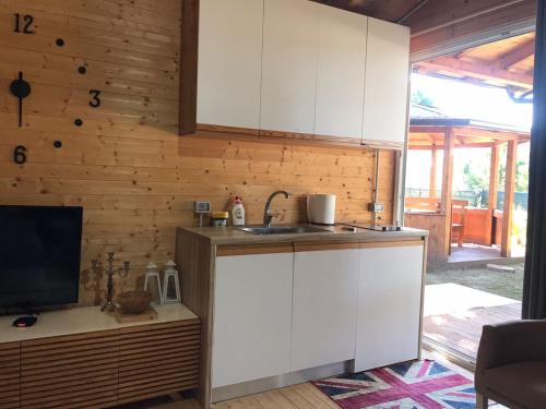 a kitchen with white cabinets and a sink and a television at Vila Gjiri Lalzit in Durrës
