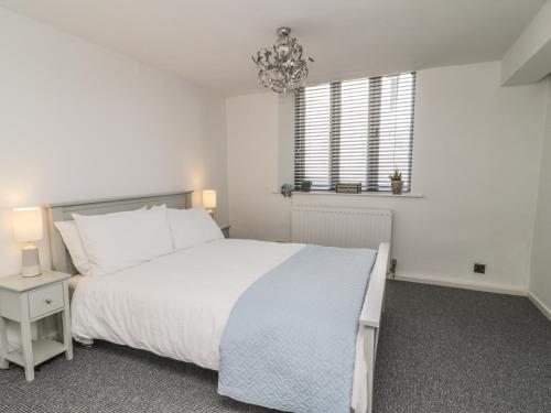 a white bedroom with a large bed and a chandelier at 11 Camden Building in Kendal