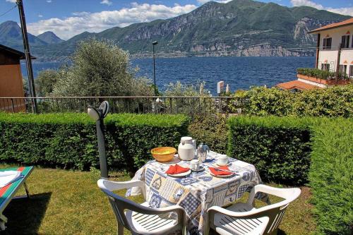 tavolo con sedie e tavolo e vista sull'acqua di Aparthotel La Caletta Bolognese a Brenzone sul Garda