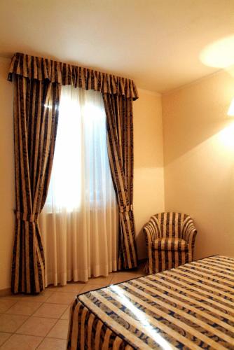 a bedroom with a bed and a window with curtains at Hotel La Maddalena in Quattro Castella