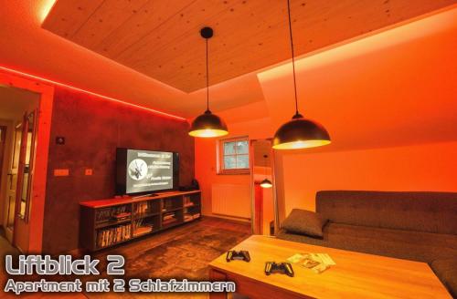 a living room with orange walls and a couch and a tv at Ferienwohnungen "Liftblick 2 oder 3" im Kurort Altenberg in Kurort Altenberg