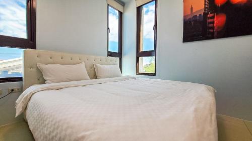a bedroom with a large white bed with windows at Touch 星空包棟民宿寵物友善民宿 in Wujie