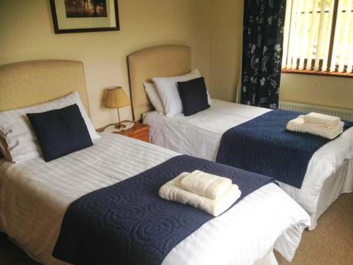 two beds in a hotel room with towels on them at Llety'r Bugail in Dolgellau