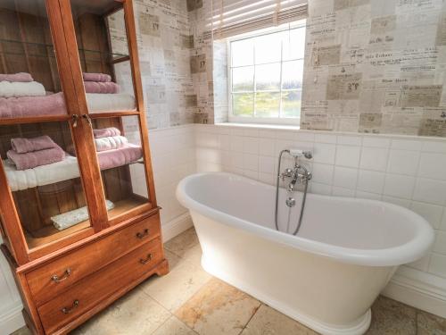a bathroom with a bath tub and a window at Thistleyhaugh Cottage in Morpeth