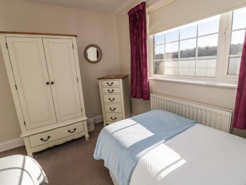 a bedroom with a bed and a dresser and a window at Thistleyhaugh Cottage in Morpeth