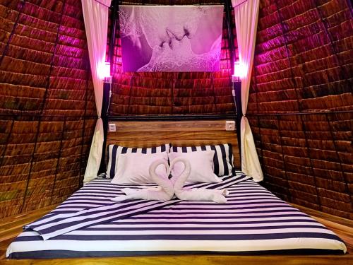 two towels on a bed in a room with pink lights at Archery-Asia Nipa Huts Moalboal in Moalboal