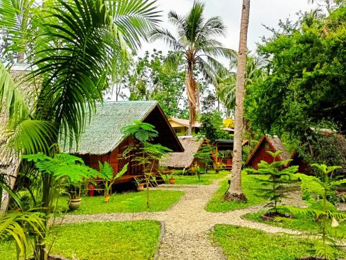a path leading to a resort with palm trees at Archery-Asia Nipa Huts Moalboal in Moalboal