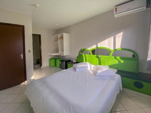 a bedroom with a white bed with green accents at GUINZA in Balneário Camboriú