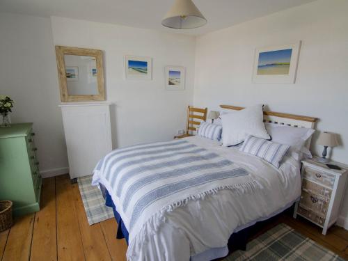 a bedroom with a large bed with a striped blanket at Eddystone Cottage in Wadebridge