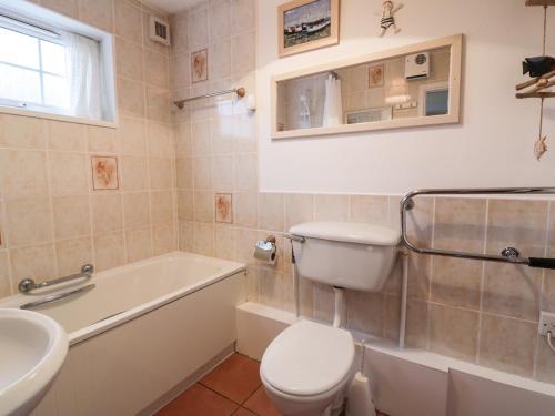 a bathroom with a toilet and a tub and a sink at Polpeor in Helston