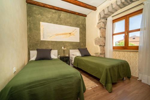 a bedroom with two beds with green sheets and a window at House Luce in Krapan