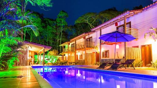 a swimming pool with two chairs and an umbrella at Pousada Vila Mangaba in Arraial d'Ajuda