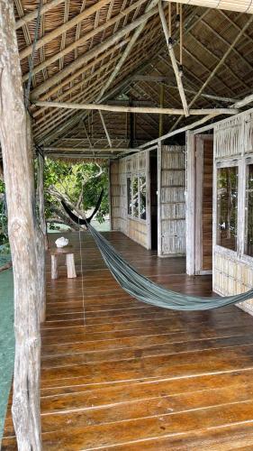 a hammock in a house with a tree at Nyande Raja Ampat in Pulau Mansuar