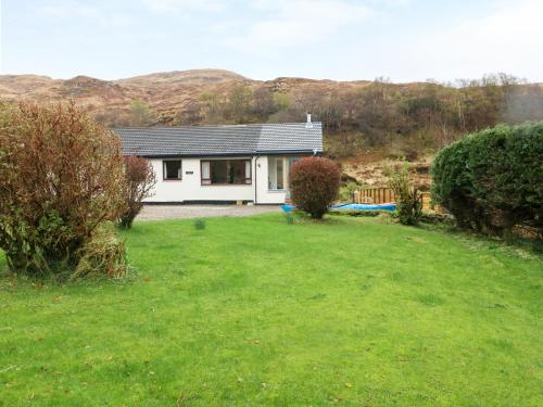 a small white house with a grass yard at Torgorm in Glenelg