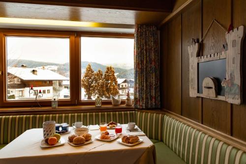 a table with plates of food in a room with a window at Hotel Martinerhof in San Lorenzo di Sebato