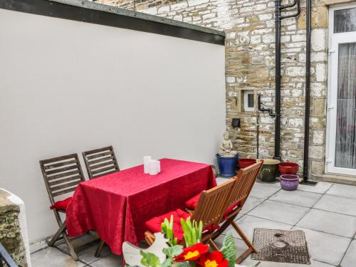 a table with a red table cloth on a patio at Angel Cottage in Skipton