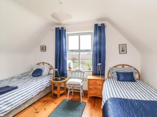 1 Schlafzimmer mit 2 Betten und einem Fenster in der Unterkunft Driftwood Cottage in Fethard on Sea