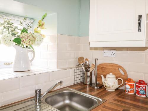 un bancone della cucina con lavandino e vaso di fiori di Pat White's Cottage a Rostrevor