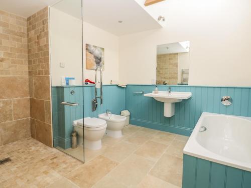 a bathroom with a shower toilet and a sink at Cow Byre in Great Habton