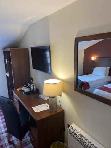 a hotel room with a desk with a bed and a mirror at Scone Arms Hotel in New Scone