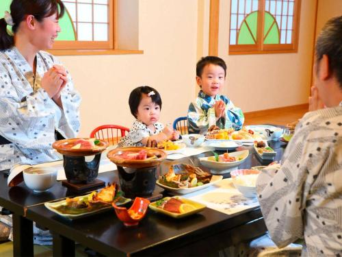 a group of people sitting around a table eating food at Hatsuneso Shinkan in Ureshino