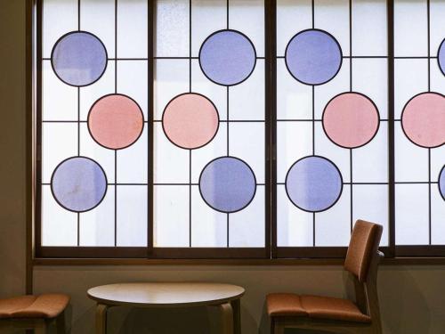 a stained glass window with two chairs and a table at Hatsuneso Shinkan in Ureshino