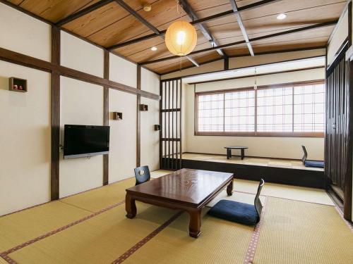 a living room with a table and a tv at Hatsuneso Shinkan in Ureshino