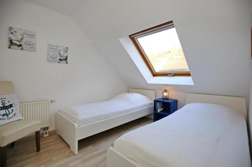 a room with two beds and a window and a chair at Papillon Wohnung 04-6 in Boltenhagen