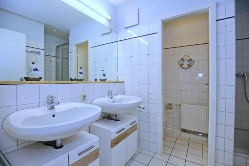 a white bathroom with two sinks and a mirror at Papillon Wohnung 04-6 in Boltenhagen