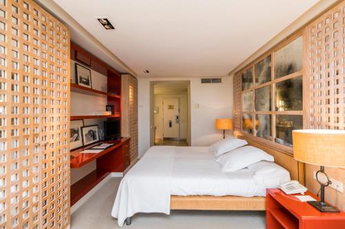 Hotel Mim Sotogrande Club Maritimo في سوتوغراندِ: غرفة نوم بسرير ذو شراشف ووسائد بيضاء