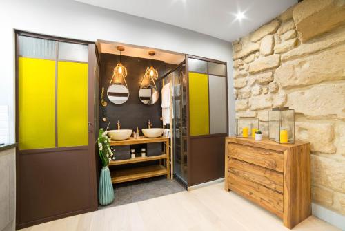 a bathroom with two sinks and a stone wall at The Sweet Luxembourg Garden in Paris