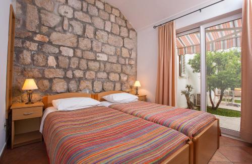 ein Schlafzimmer mit einem Bett und einer Steinmauer in der Unterkunft Apartments Benussi in Dubrovnik