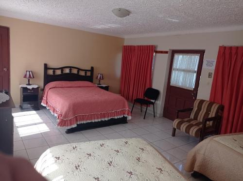 a bedroom with a bed with a red comforter at Hostal Aramayo in Tupiza