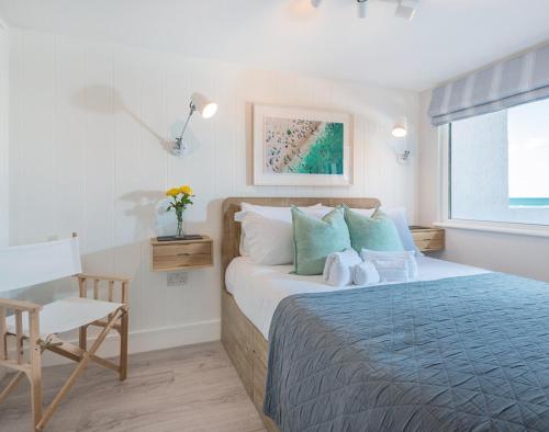a bedroom with a bed and a chair and a window at Tide Pod in Wadebridge