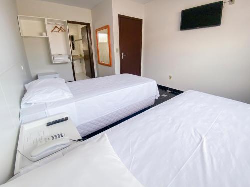two beds in a hotel room with a phone between them at GUINZA in Balneário Camboriú
