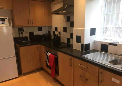a kitchen with wooden cabinets and a black counter top at 2 Bedroom House For Corporate Stays in Kettering in Kettering