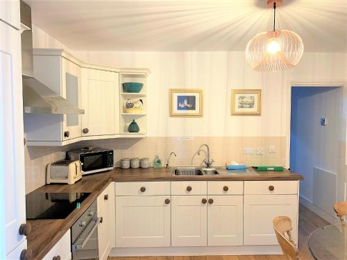 a kitchen with a sink and a microwave at Riverside Channel5 "Holidays Homes in the Sun" Featured Central Canterbury Cottage with Free Parking in Canterbury