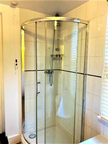 a shower with a glass door in a bathroom at Elegant Riverside Cottage With Free Parking in Canterbury