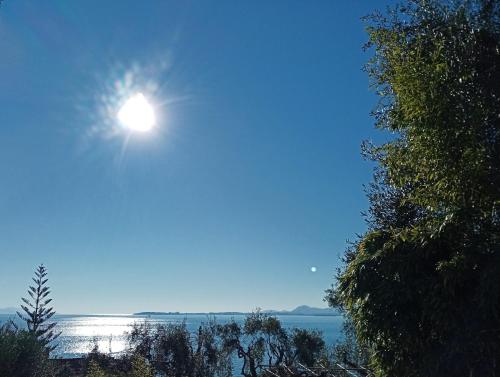 a sun shining in the sky over a body of water at Kiki's Apartments in Barbati