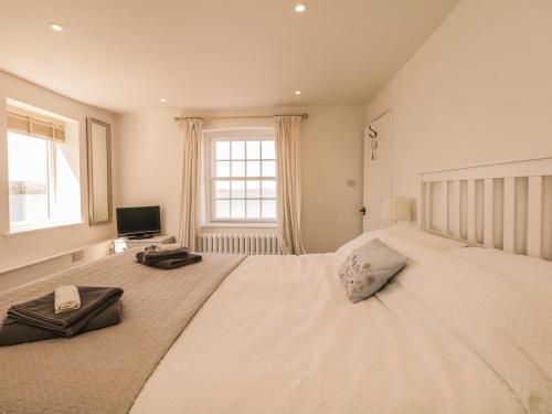 a bedroom with a large white bed with a television at Searles in Lympstone