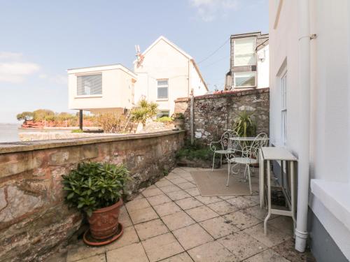 a patio with a table and chairs on a wall at Searles in Lympstone