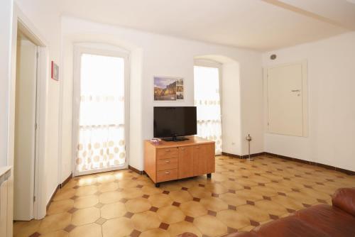 a living room with a tv on a dresser and two windows at Da Elisa in Riomaggiore