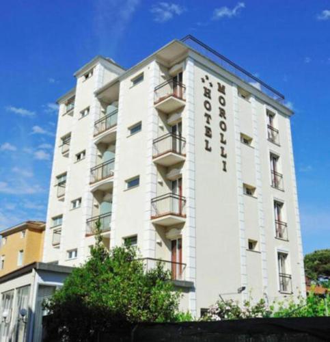 a tall white building with a sign on it at Hotel Morolli in Rimini