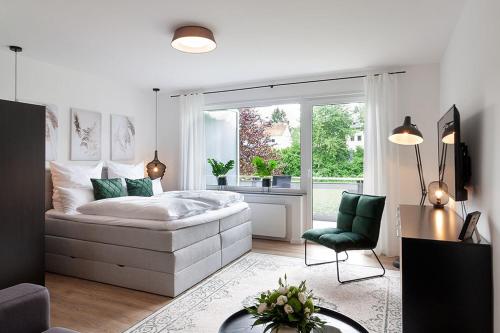 um quarto com uma cama, uma cadeira e uma janela em Modernes Apartment *Liobablick Nr. 2* - FeWo in Fulda/Petersberg em Petersberg
